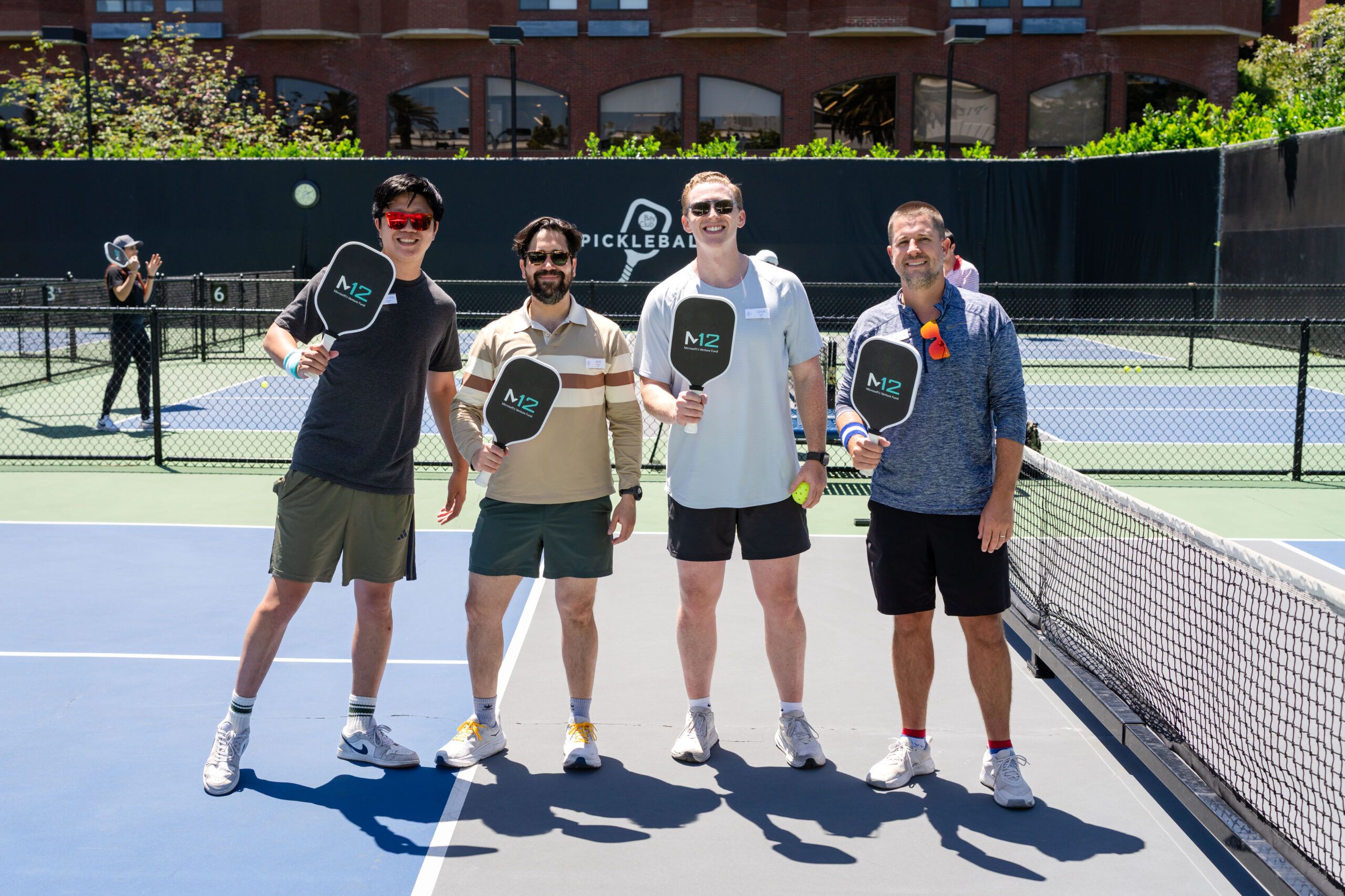 m12 event photography sf scaled db440e69 Participants pose for a group photo during the M12 Founder Summit pickleball event in San Francisco, photographed by Luma Creative.