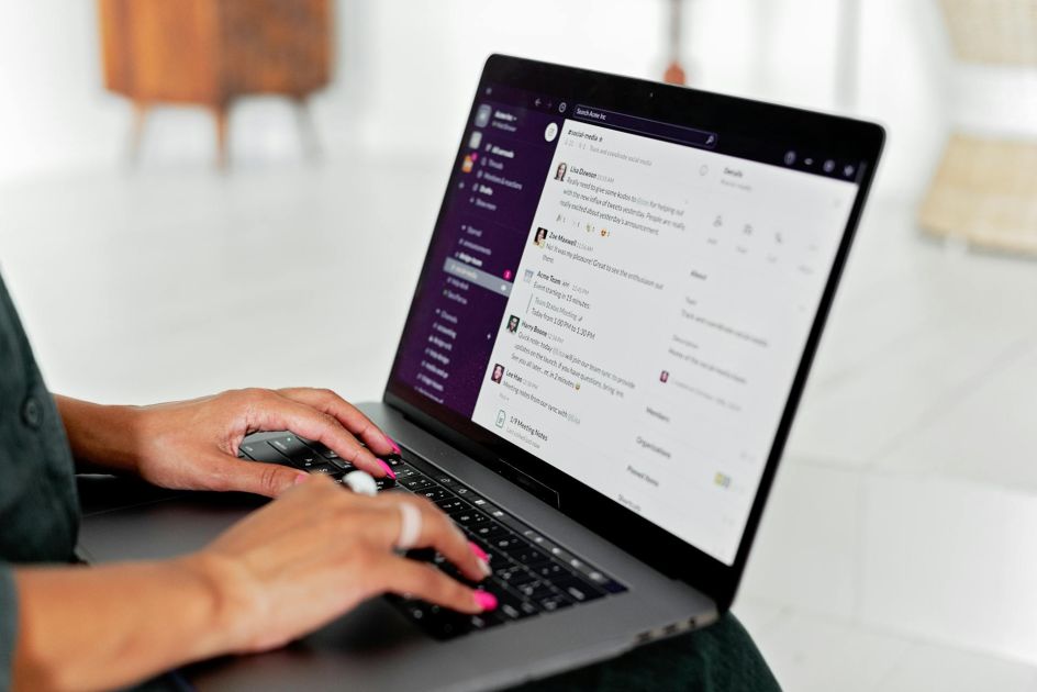 Person managing freelancers by typing messages on Slack app on a laptop