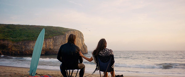 Couple watching the sunset from beach chairs with a surfboard on a Northern California beach, frame from Sitpack's launch video by Luma Creative